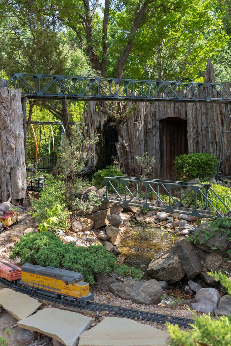 Model trains rolling through a garden