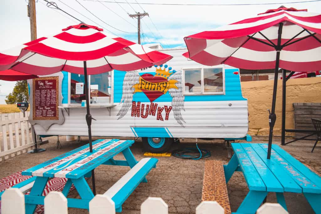 A food truck with a red and white umbrella