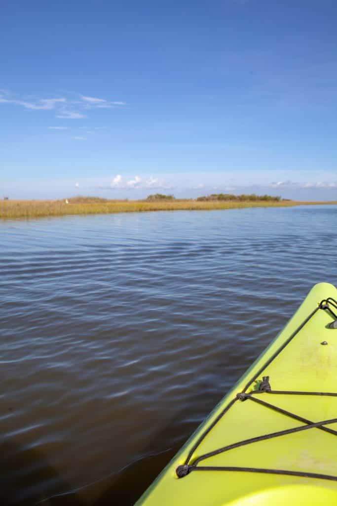 A bright yellow kayak glides on calm water