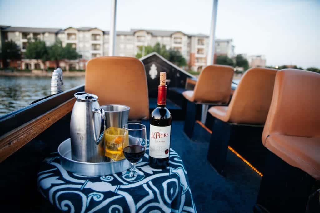 A boat interior with brown seats and a table holding a wine bottle