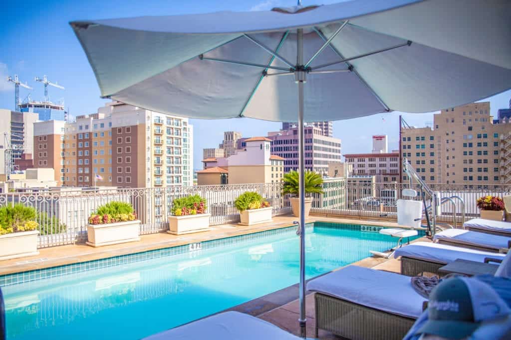 Rooftop pool and umbrella, city skyline in the background.