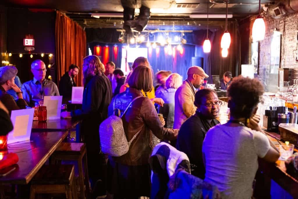 People gather in a bar, surrounded by glowing red lights