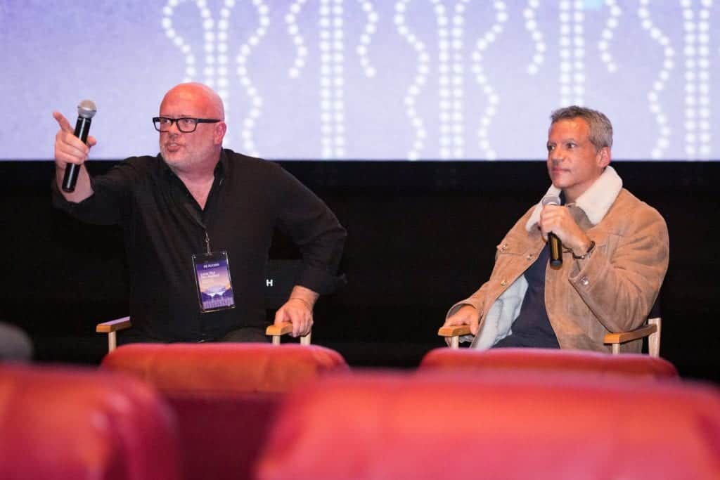 Two men sit comfortably in theater chairs