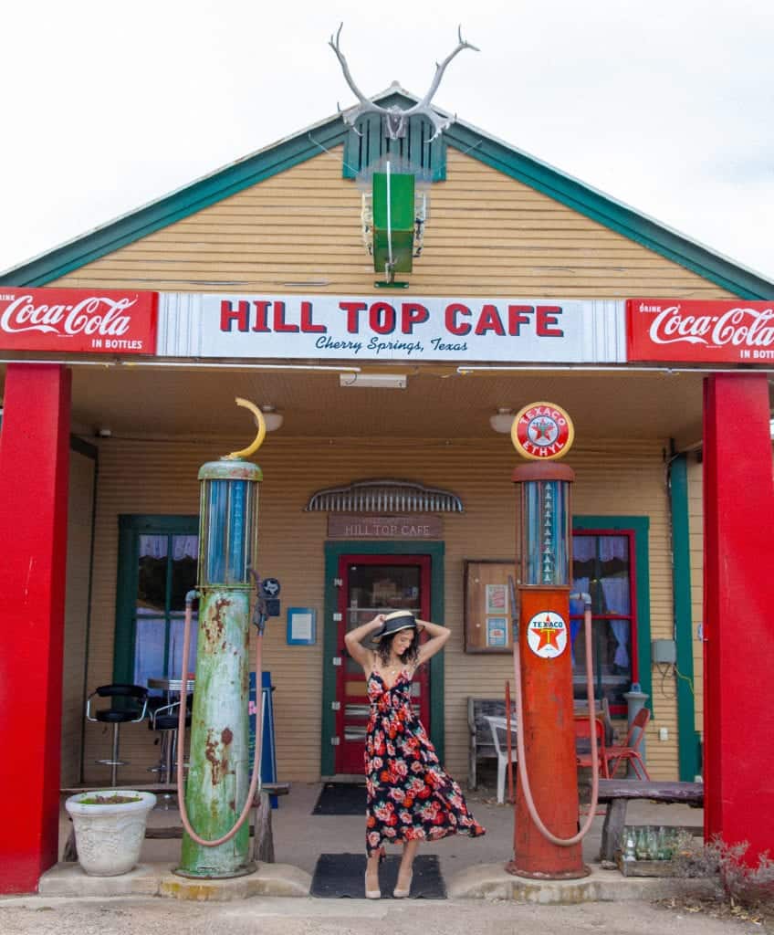 a person in a dress posing for a picture in front of a gas station