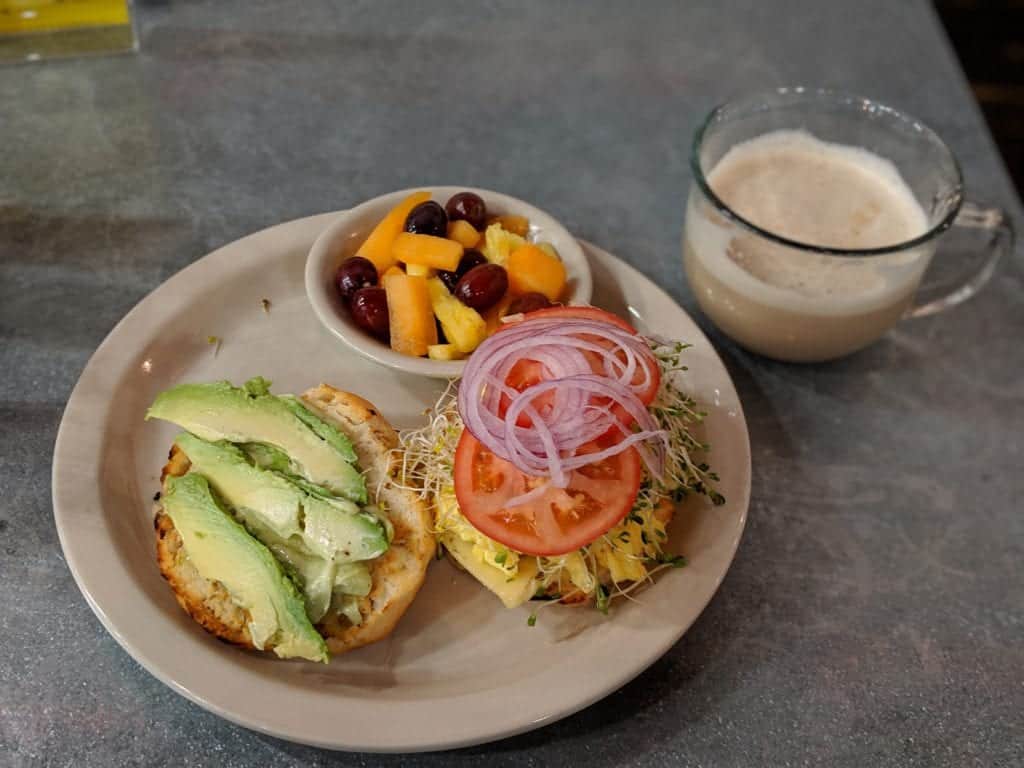 a plate of avocado toast, fruits and a drink