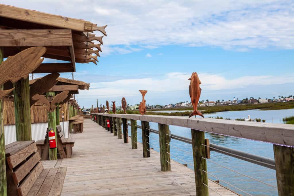 Wooden pier with carved fish post tops and a clear sky