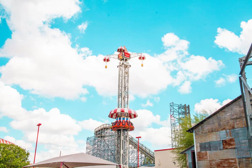 a tall metal tower with a slide and a blue sky with clouds