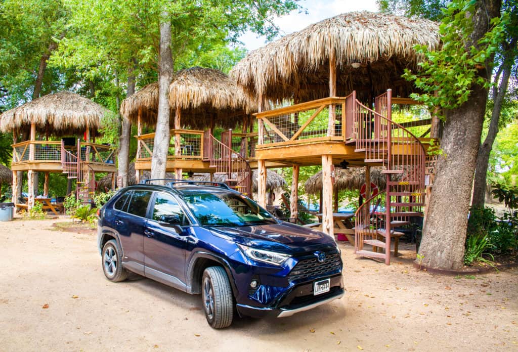 a blue car parked in front of a hut