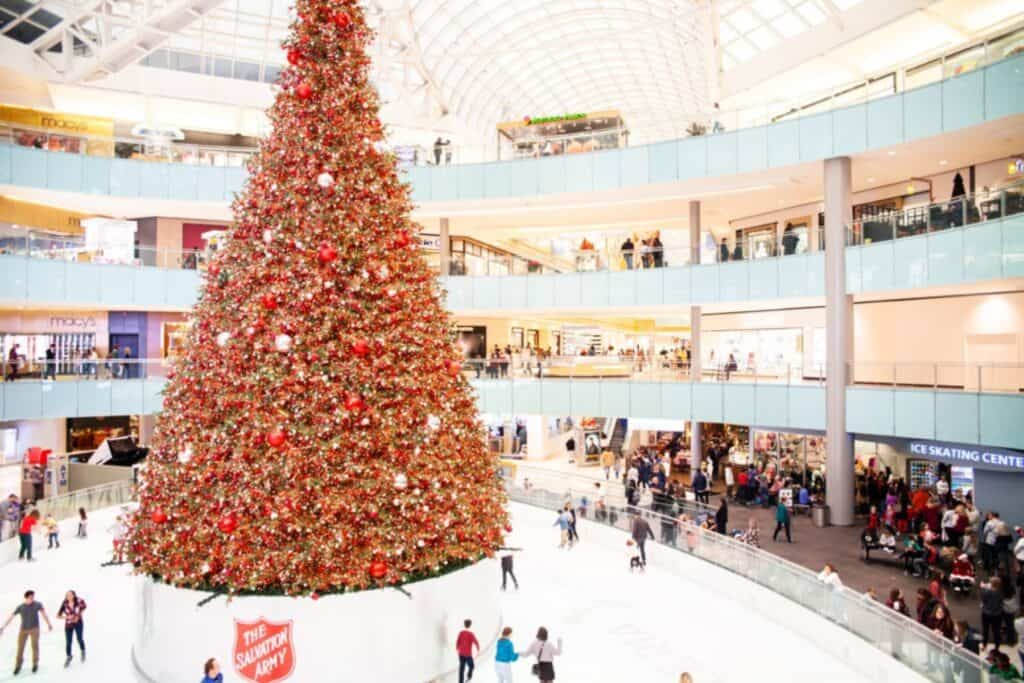 People ice skating around an indoor Christmas tree