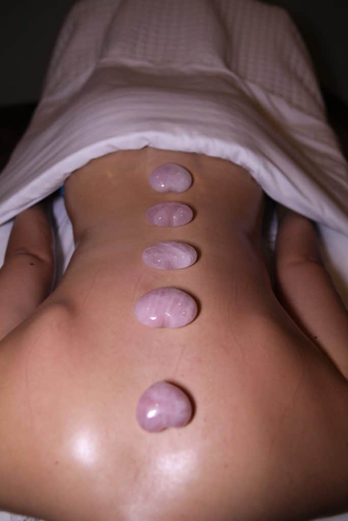 a person lying down with pink stones on their back