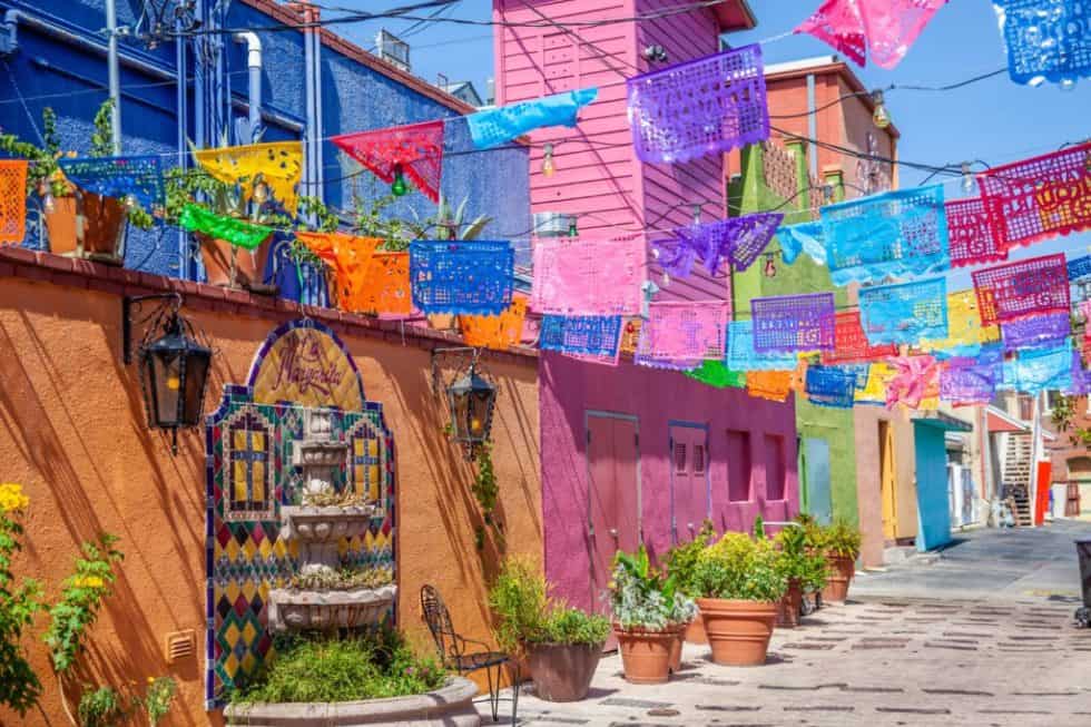 a colorful street with flags and a fountain