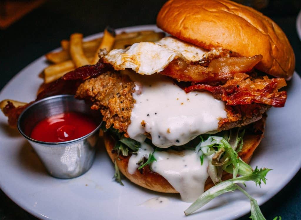 a burger with bacon and sauce on a plate