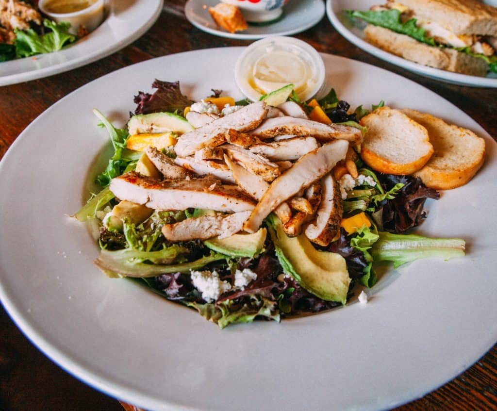 a plate of salad with chicken and avocado