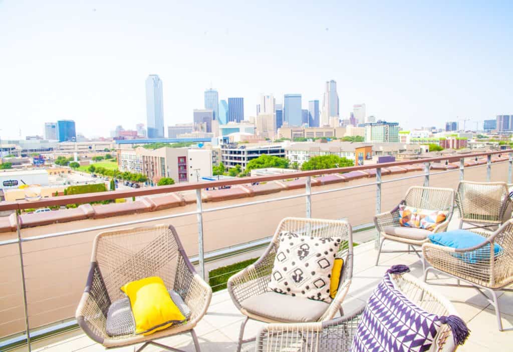  A balcony with chairs overlooks a Dallas city skyline