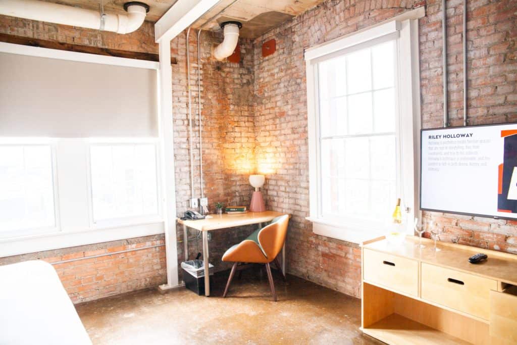 cozy bedroom featuring a desk, chair, and a television in Canvas Hotel Dallas