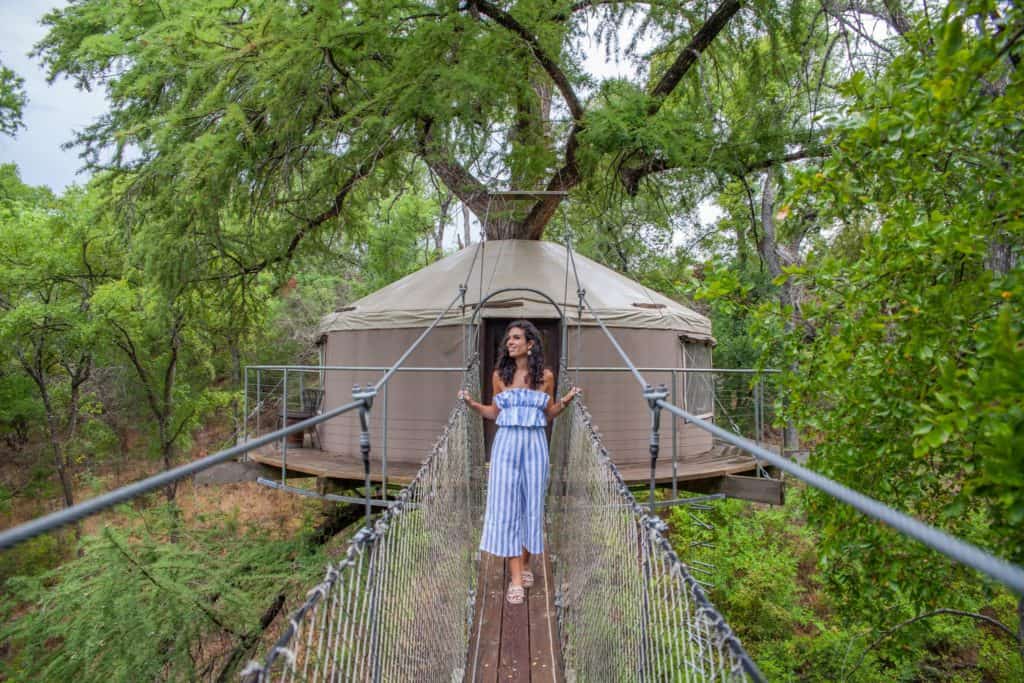 a woman in a blue dress standing on a suspension bridge