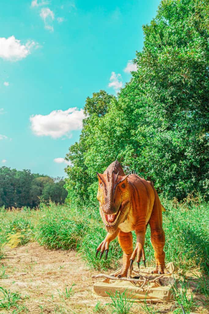 a dinosaur walking in the grass