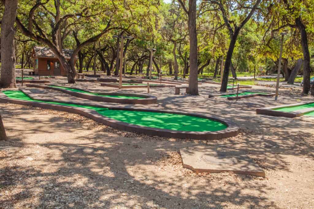 An empty outdoor mini-golf course with green carpets