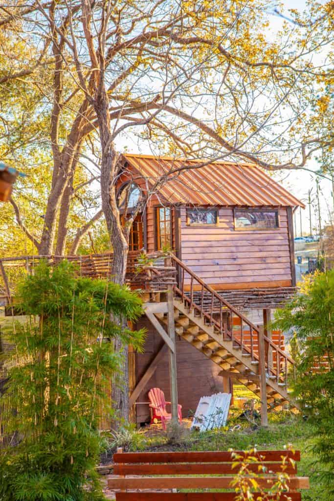 a tree house with stairs and chairs in the back