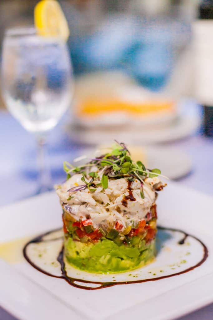 A white plate with a fresh salad beside a glass of red wine