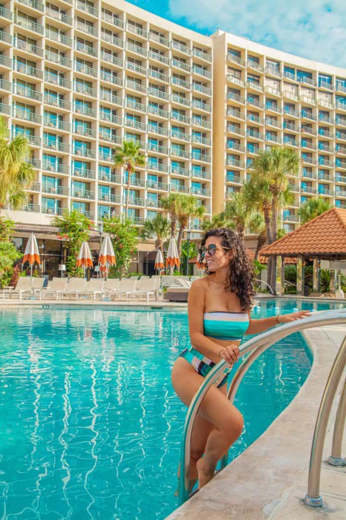 Jessica in a bikini leans on San Luis Resort pool railing