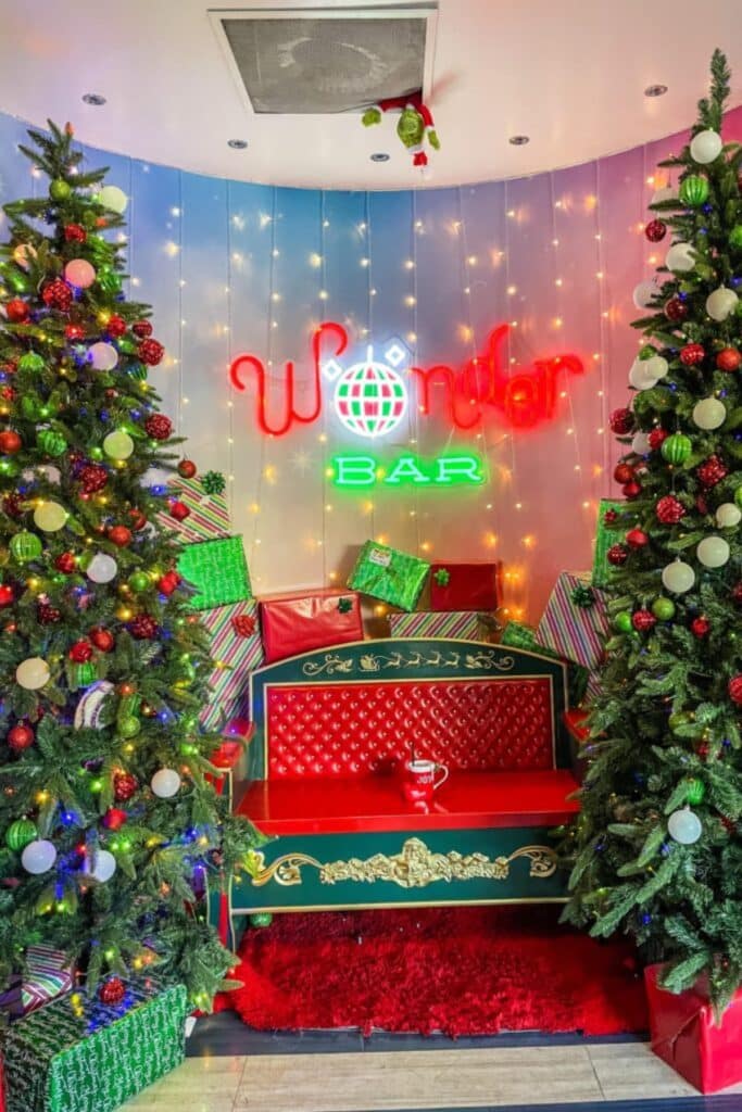 Sleigh chair with Christmas trees on either side and a sign over it that says "Wonder Bar"
