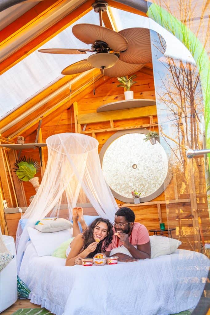 A couple sits together on a bed in a cozy tiny house