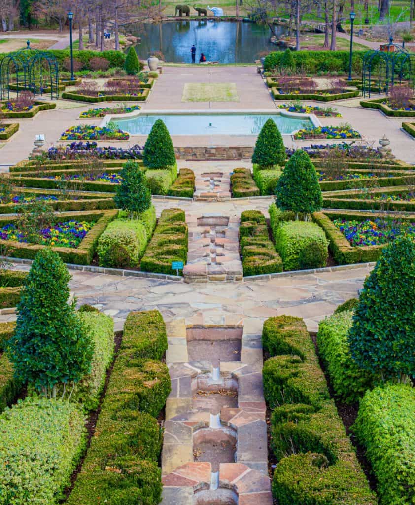 a garden with a fountain and a stone walkway