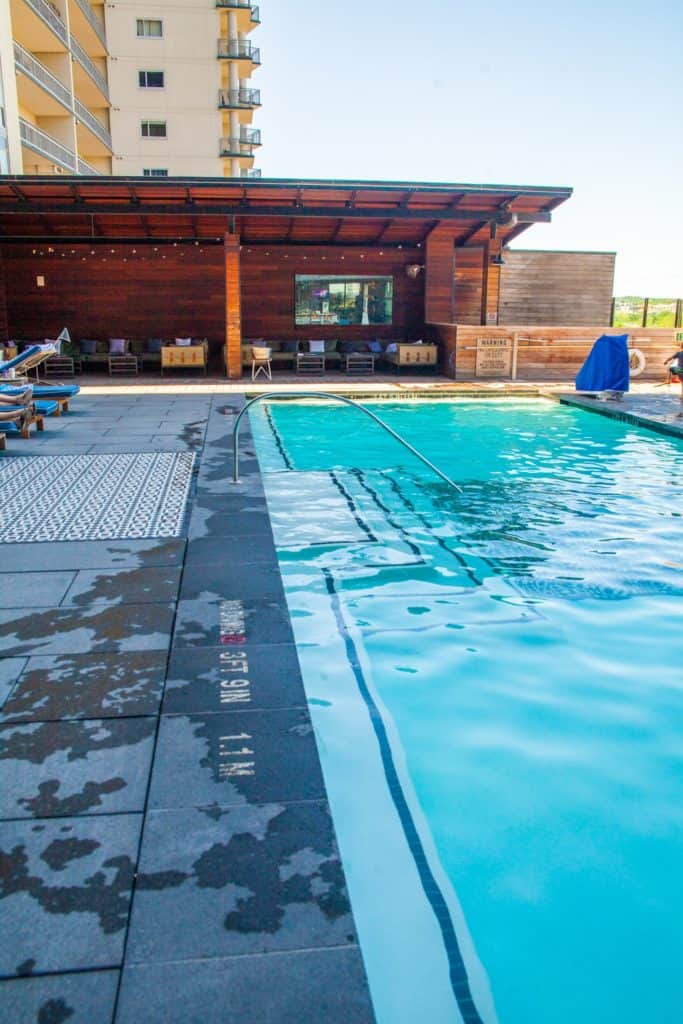 A sparkling swimming pool surrounded by lounge chairs and a wooden cabana at hotel van zandt