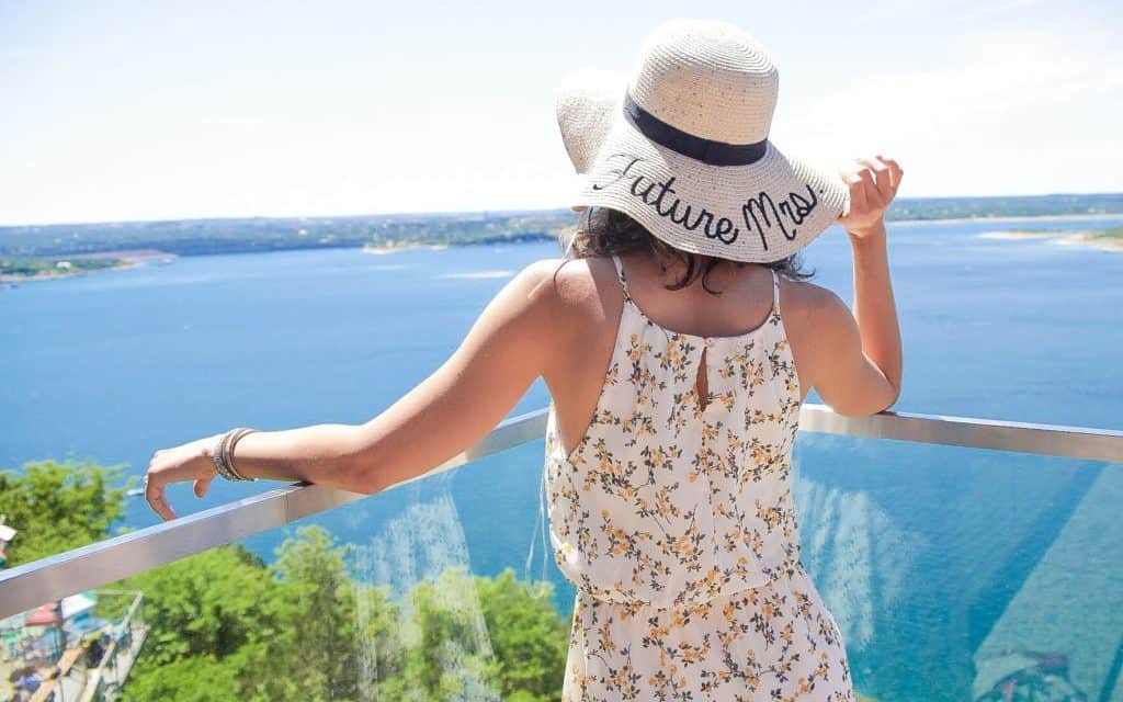 a woman wearing a hat and looking at the ocean