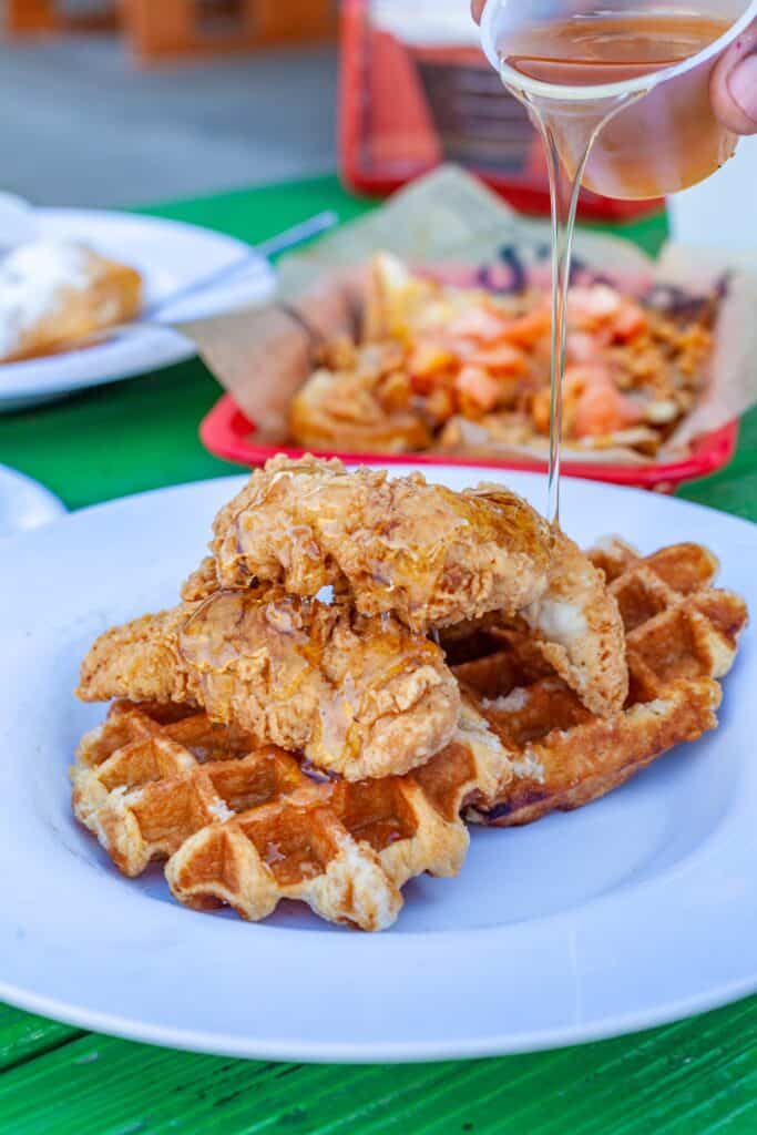 a person pouring syrup onto a waffle