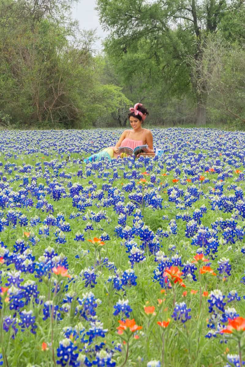 A woman enjoying a peaceful moment amidst a beautiful field of bluebonnets, surrounded by nature's vibrant colors.