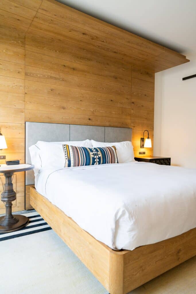 a wooden accent wall, a cozy bed with decorative pillows, and stylish bedside lamps at the Canopy by Hilton