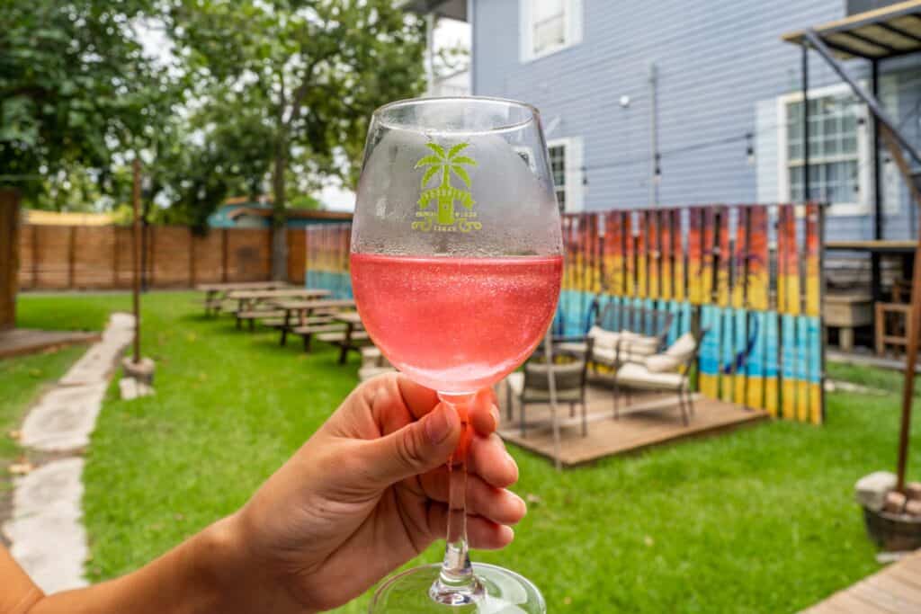 a hand holding a glass of pink liquid