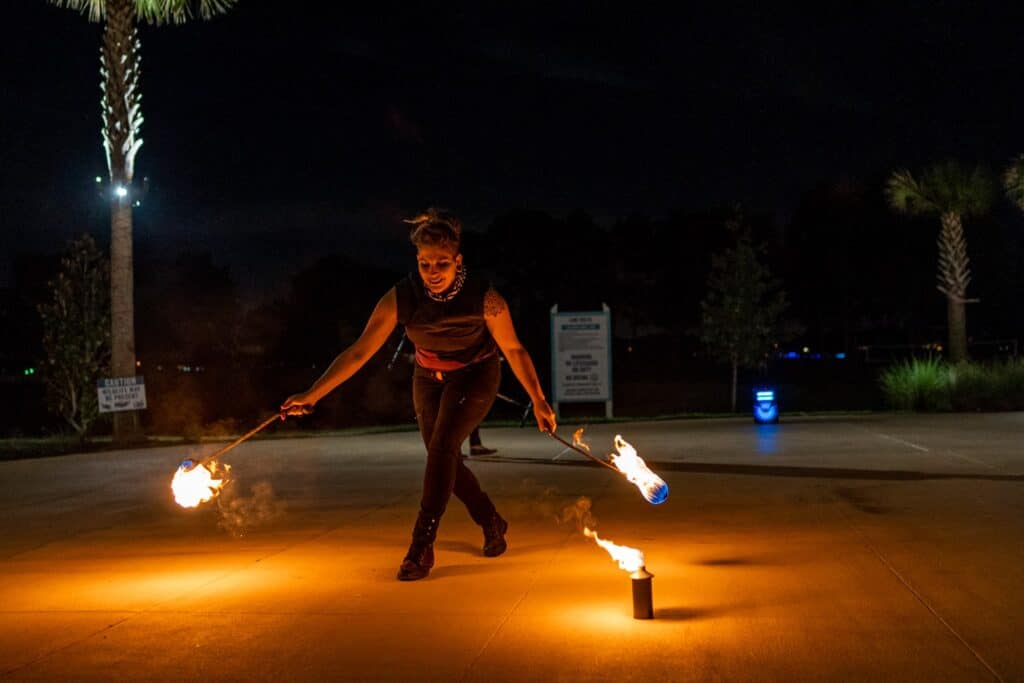 a person holding two torches and fire