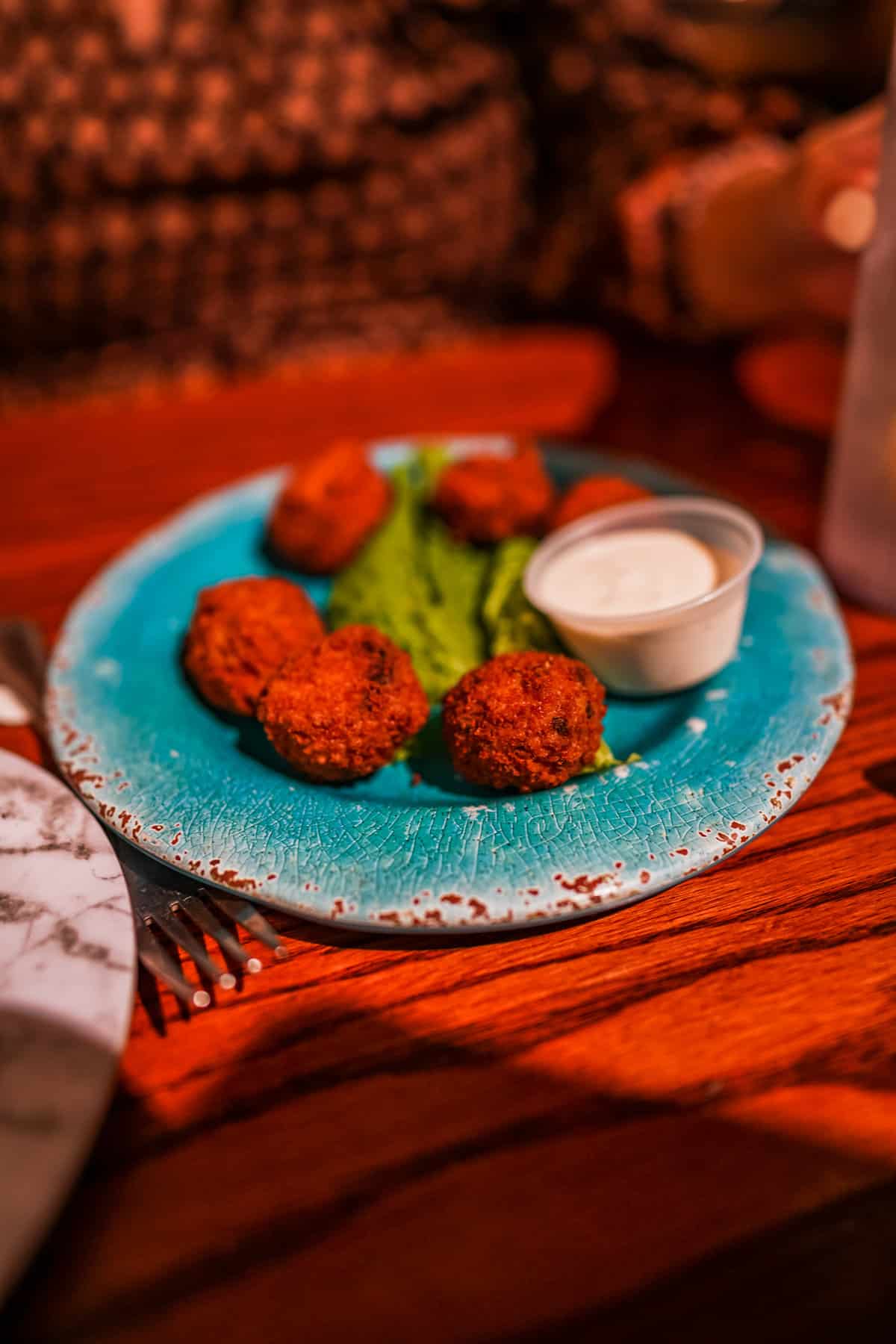 A teal plate holds five golden-brown fried balls