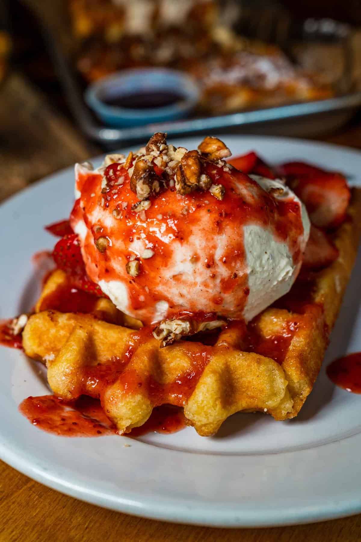 Strawberry syrup with vanilla ice cream over a waffle 