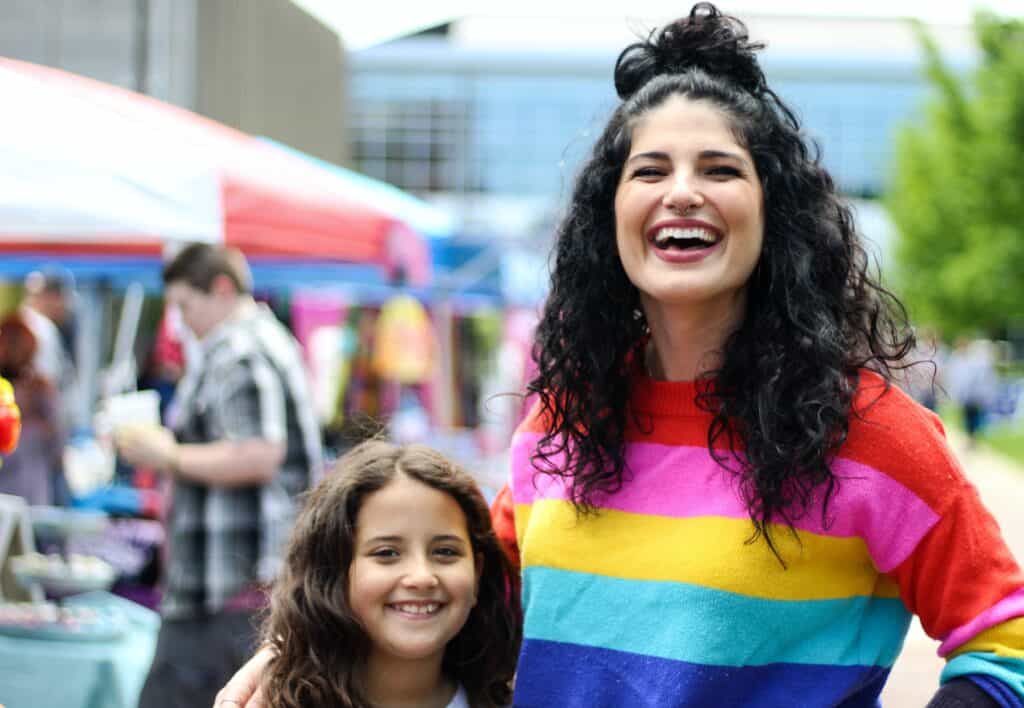 A mother and daughter smiling in rainbow clothing