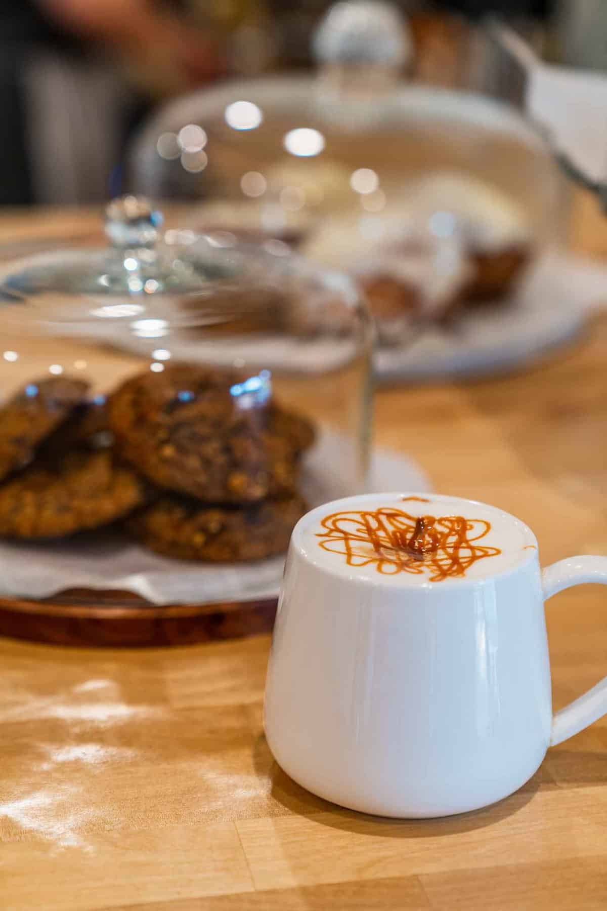 A cup of cappuccino with chocolate cookies at the background