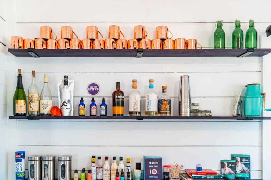 Hanging Shelves with Alcoholic Drinks, Dyes, Syrups and Mugs