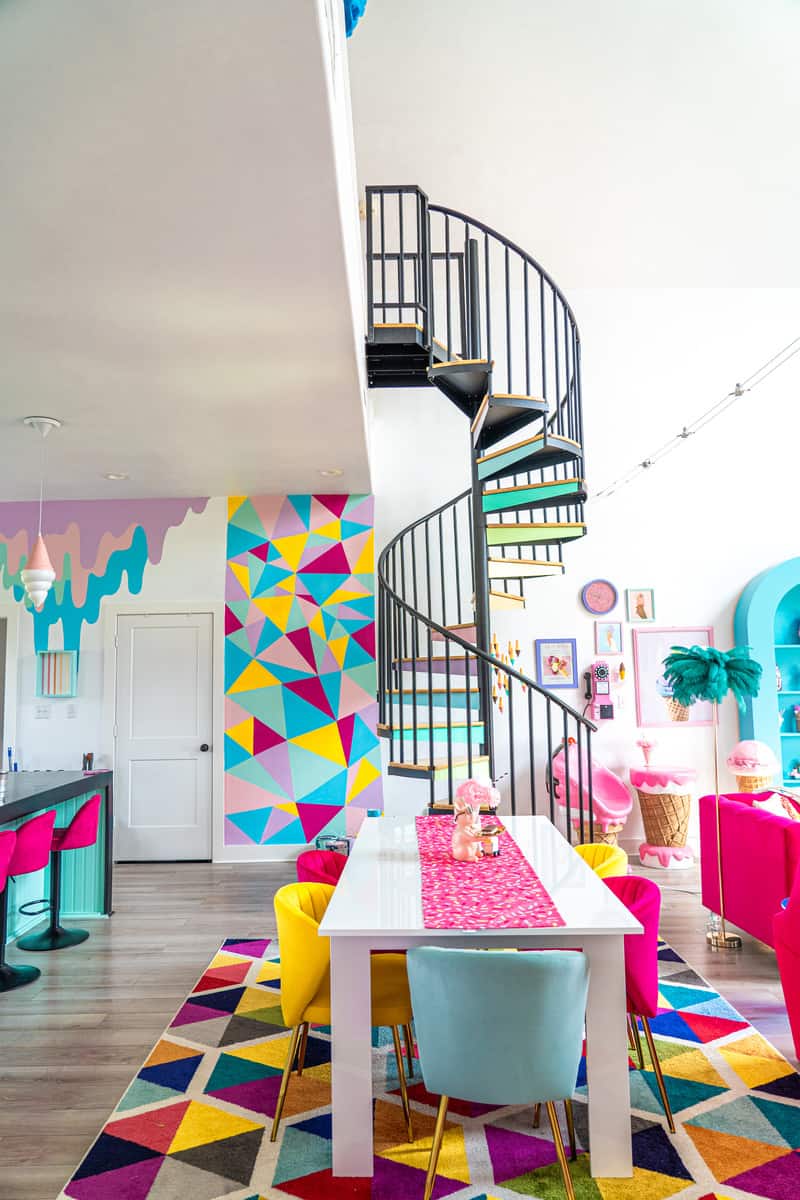 pastel rainbow winding staricase with table and geometric mural on the wall