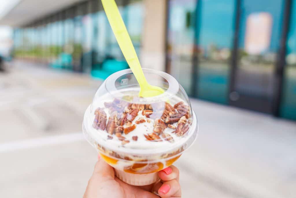 a hand holding a plastic cup with a spoon in it