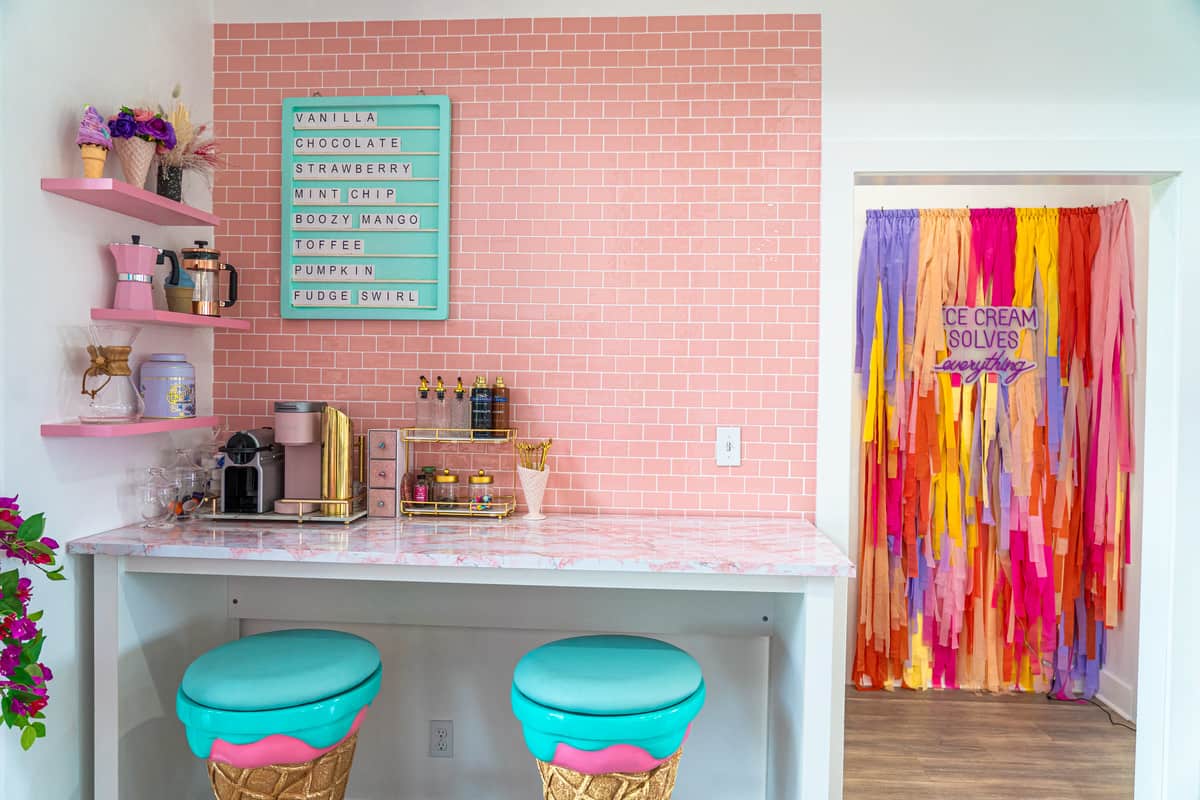 coffee bar with pink bricks wall paper and ice cream shaped bar stools
