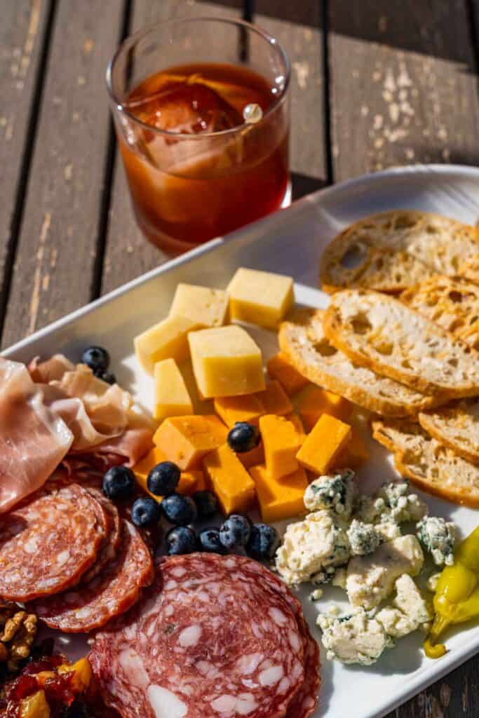 charcuterie board with drink on a glass