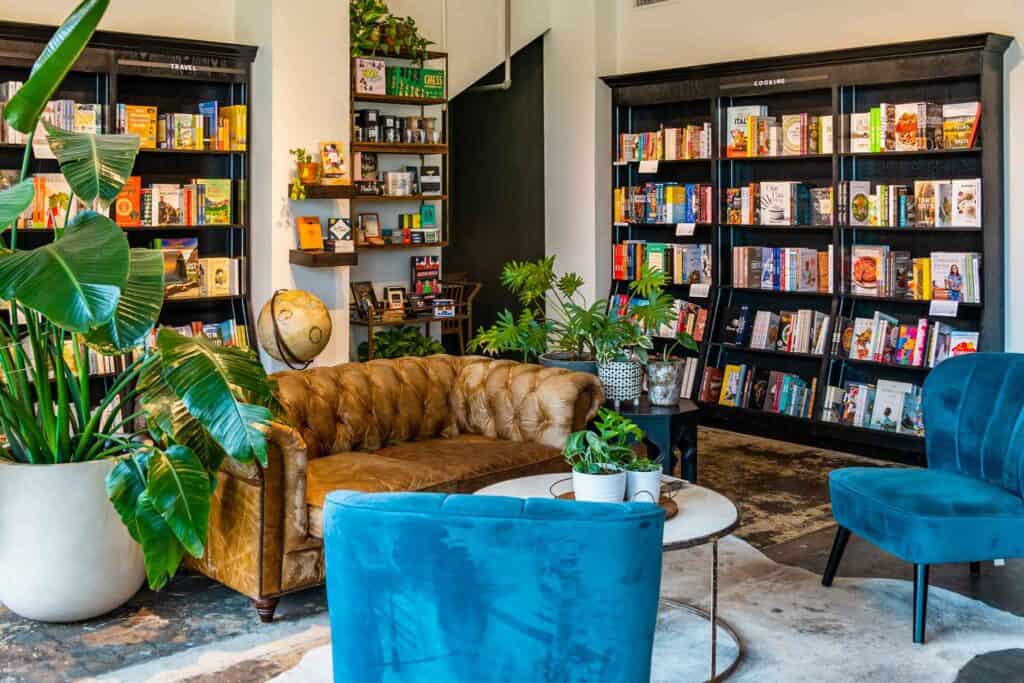 Comfy leather couch surrounded by green plants and shelves of books at Fabled Coffee