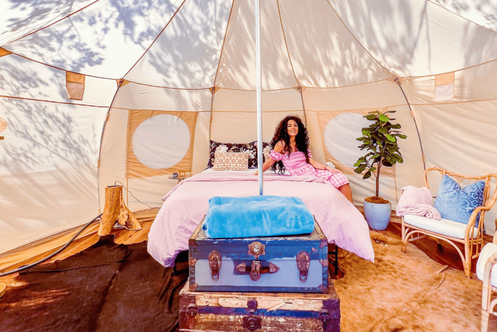 Lady sitting on the bed of a glamping tent