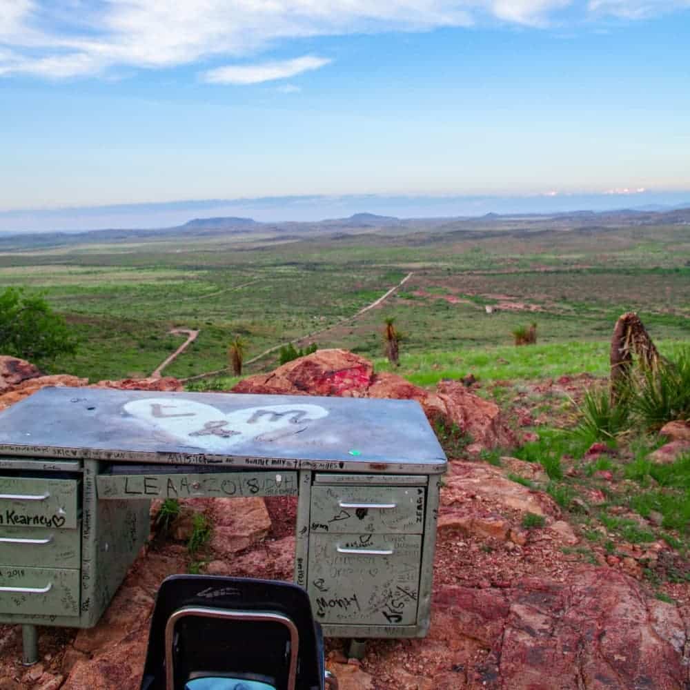 A metal desk with a chair sitting on the edge of a cliff