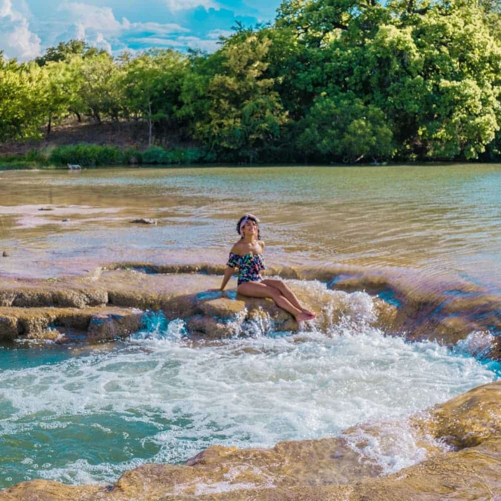Woman sitting inside a naturally occurring jacuzzi tub in the middle of a lake