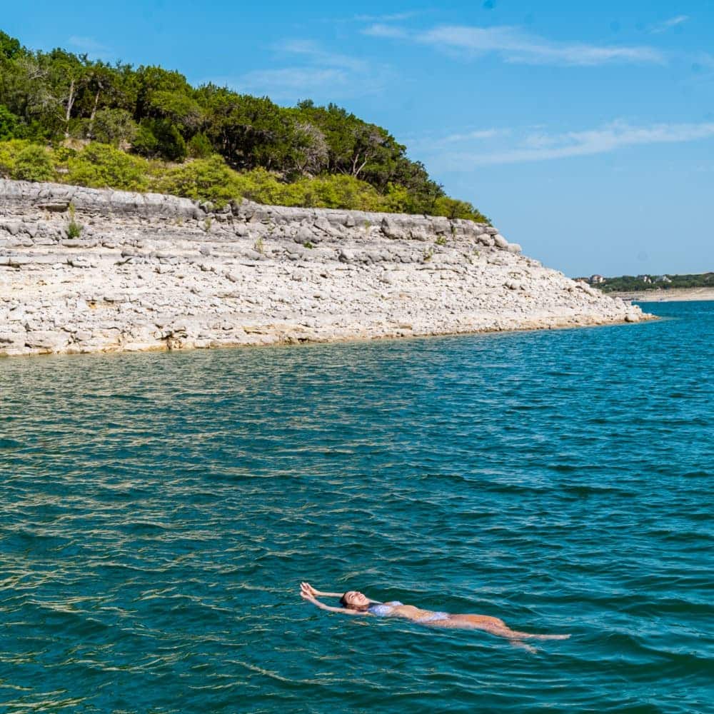Woman floating on her back in the middle of Lake Travis