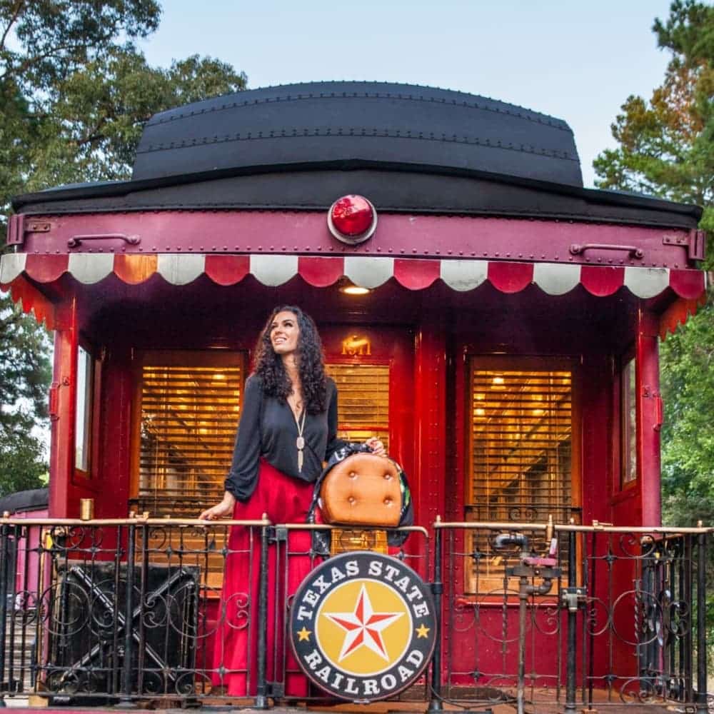 Woman standing on a caboose with a Texas State Railroad sign